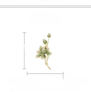 Detail einer vergoldeten Blumenbrosche mit grünen Zirkonen und weißen Kristallen