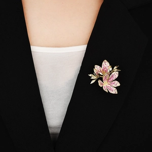 Elegant gold flower brooch with pink zircons on a black blazer for high-end fashion styling