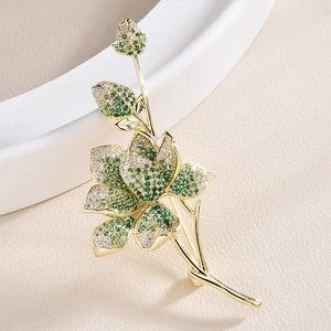Eleganter Blumenanstecker mit grünen Zirkonia Steinen in goldener Fassung für Damen