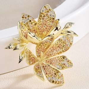 Elegant gold flower brooch with colorful cubic zirconia gradients on white ceramic