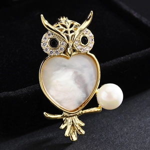 Elegant owl brooch with white mother of pearl heart and large pearl on black velvet