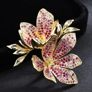 Elegant gold flower brooch with purple and white cubic zirconia on black background