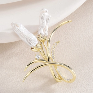 Elegant gold flower brooch with baroque pearls and sparkling zircons on white leather