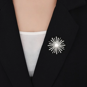 Detailed view of a silver sunburst brooch with pearl and rhinestones on a black suit lapel
