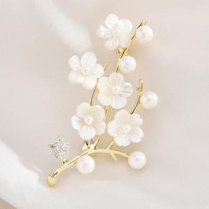 Elegante spilla a fiore dorata con perle e zirconi su sfondo di seta bianca