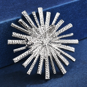 Back view of silver sunburst brooch with safety pin buckle on textured blue display box