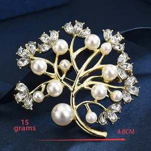 Detail einer goldenen Baum-Brosche mit weißen Perlen und Strass auf blauem Seidengewebe