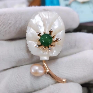 Vue macro d'une broche fleur en nacre avec perle verte et perle d'eau douce rose