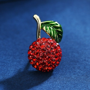 Broche cerise élégante avec cristaux rouges et feuilles dorées sur tissu bleu foncé