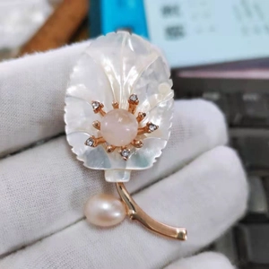 Détail d'une broche feuille en nacre avec pierre rose et perle en forme de goutte d'eau