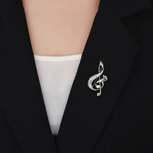 Elegant music note brooch with rhinestones and pearl on a black suit lapel detail