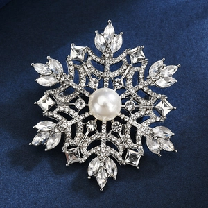 Elegante Schneeflocken-Brosche mit weißer Perle und funkelnden Kristallen auf Samt