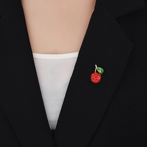 Gros plan détaillé d'une broche cerise rouge scintillante sur le revers d'un tailleur