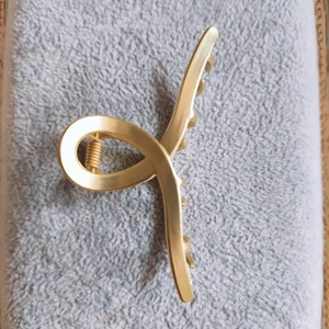 Détail d'une pince à cheveux en métal doré mat avec un mécanisme à ressort robuste