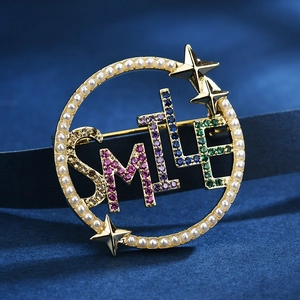 Goldene SMILE Brosche mit bunten Zirkoniasteinen und weißen Perlen auf Samtgrund