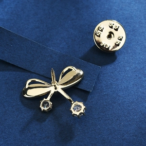 Broche papillon dorée avec zircons montrant l'épingle arrière et le fermoir métallique