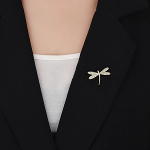 Edle goldene Libellen-Brosche mit Zirkonia-Steinen auf einem schwarzen Damen-Blazer