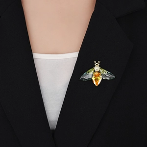 Detailed view of an insect brooch with green gradient wings on a black suit lapel