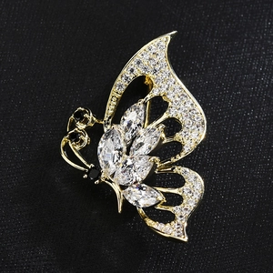 Élégante broche papillon en or avec zircons marquise et cristaux sur fond noir texturé