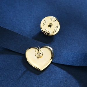 Elegant gold heart brooch pin with secure butterfly clasp on deep blue textured background