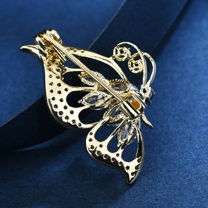Broche papillon dorée avec pierres de zircon et détails d'ailes creuses sur fond bleu