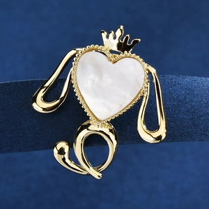 Broche chiot dorée avec opale en forme de cœur blanc et couronne sur fond bleu foncé
