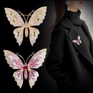 Detail view showing intricate zircon butterfly brooches in yellow and magenta on a dark base