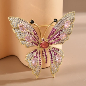 Elegant gold-plated butterfly brooch with pink and red zircon stones on a soft pink stand