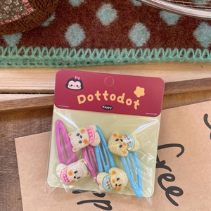 Detail of four knitted bear hair clips for children with snap-on clips in a retro setting