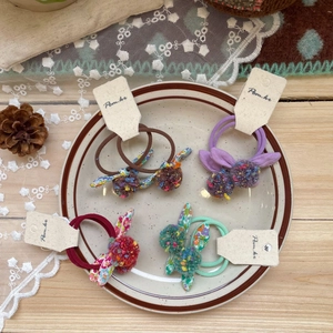 Set of four colorful rabbit ear pom pom hair ties with floral fabric and elastic bands