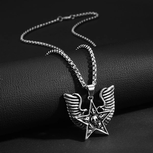 Detalle de colgante estrella punk con calaveras y alas de pluma sobre cuero negro