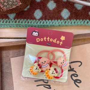 Close-up of cute cartoon dog charms on red elastic hair ties with branded packaging