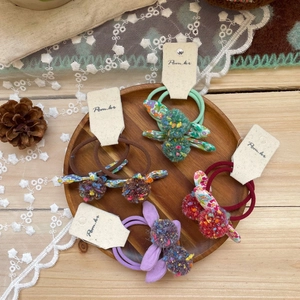 Colorful Korean-style pom pom bunny ear hair ties set on a rustic wooden tray decoration