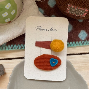 Detail von niedlichen Blumen-Pompons und Herz-Haarspangen auf der Karte