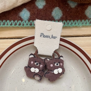 Détail de deux élastiques à cheveux ours en peluche marron avec broderie fine