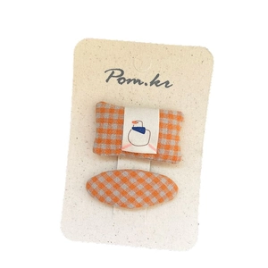 Set of two orange checkered fabric hair clips with bird motif on white display card