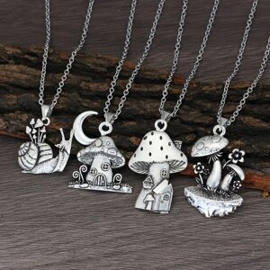 Detalle de cuatro colgantes de plata vintage con motivos de setas y cuentos del bosque