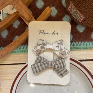 Detail of plaid and floral bow hair clips on a card for girls' hairstyling accessories