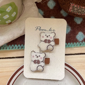 Détail de deux jolies barrettes ours en peluche blanche avec nœuds marrons sur carte