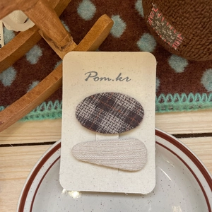 Detail view of plaid and beige knitted hair clips set on a stylish product display card