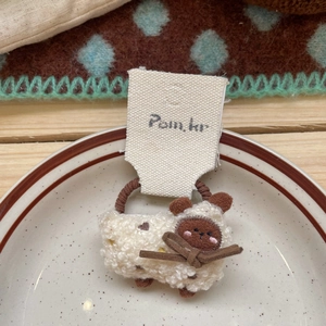 Détail d'un chouchou en peluche agneau avec nœud marron sur élastique haute qualité