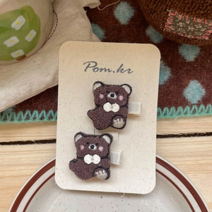 Vue détaillée de deux pinces à cheveux brodées en forme d'ours brun sur carte