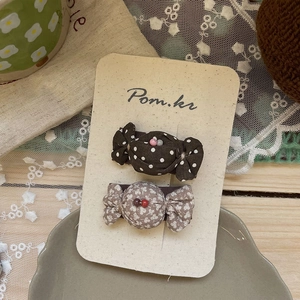 Détail de pinces à cheveux en tissu en forme de bonbon avec motifs à pois et fleurs