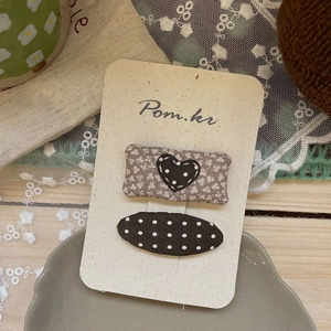 Détail de pinces à cheveux en tissu à motifs floraux et à pois sur carte cadeau