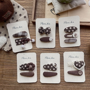 Vintage brown fabric hair clips set with polka dots and bows on wood background