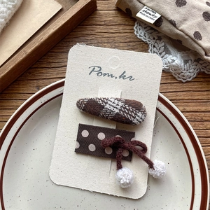 Detail of vintage brown polka dot and plaid fabric hair clips set on wooden surface