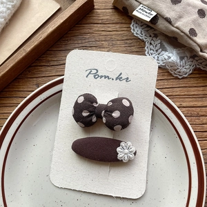 Detail of coffee-colored polka dot bow hair clips and woven flower hairpin set