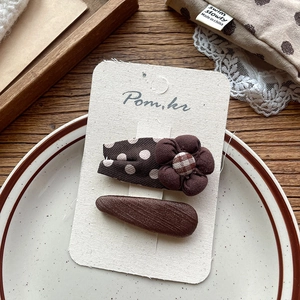 Detailed view of brown retro fabric hair clips with polka dots and floral texture
