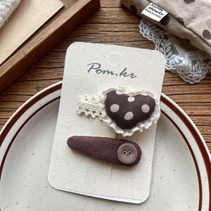 Detail of brown polka dot hair clips with lace trim and buttons on display card