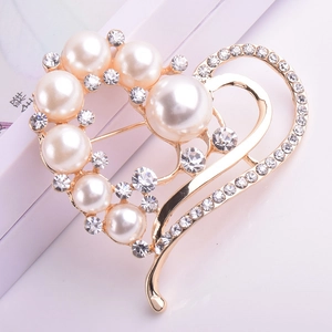 Élégante broche cœur dorée avec perles blanches et strass brillants sur un fond blanc neutre